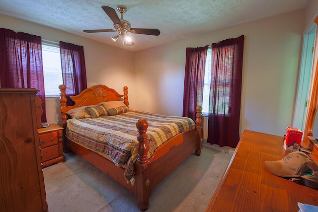 bedroom with light carpet, ceiling fan, and a textured ceiling