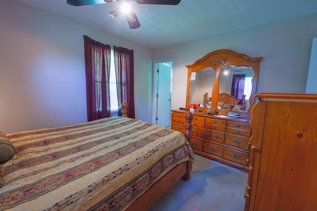 bedroom featuring dark colored carpet, multiple windows, a textured ceiling, and ceiling fan