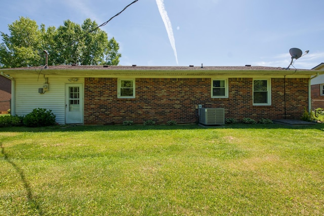 rear view of house with central AC unit and a lawn