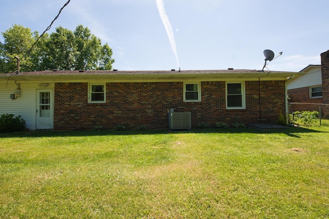 back of property with central AC and a yard