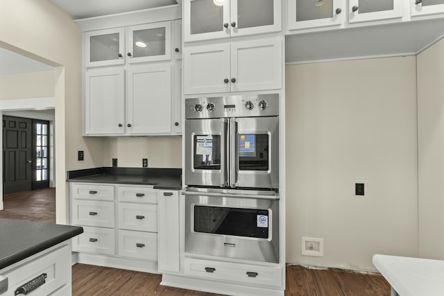 kitchen with white cabinets, dark wood-type flooring, and stainless steel double oven