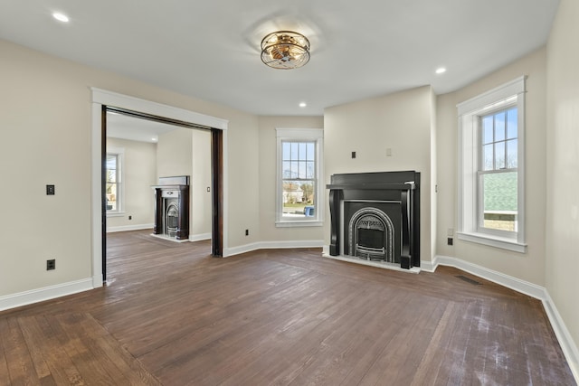 unfurnished living room with dark wood-type flooring and plenty of natural light