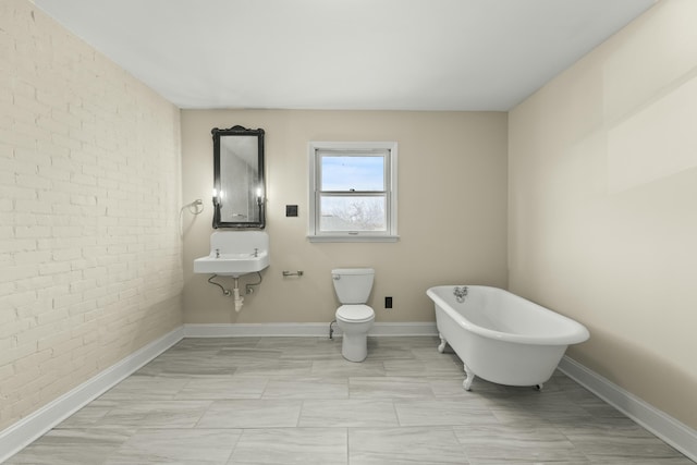 bathroom with brick wall, toilet, and a bathtub