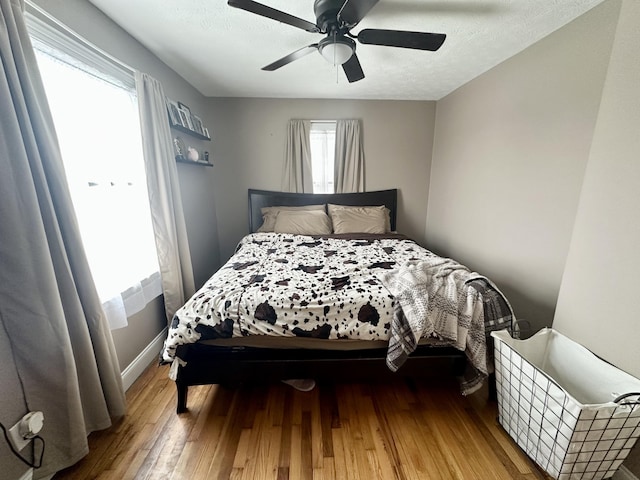 bedroom featuring ceiling fan, wood-type flooring, and a textured ceiling