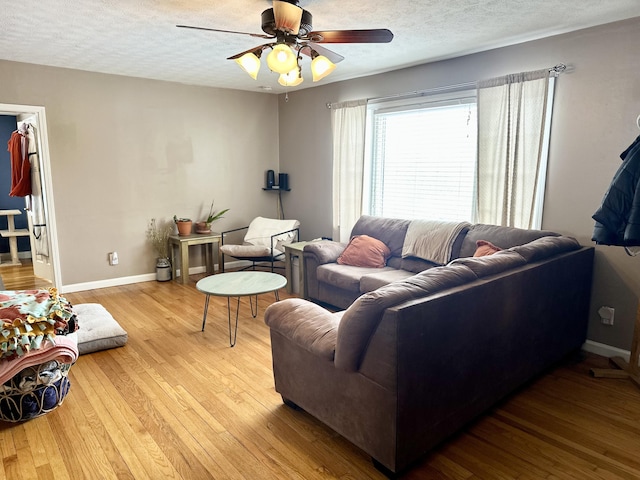 living room featuring ceiling fan, light hardwood / wood-style flooring, and a textured ceiling