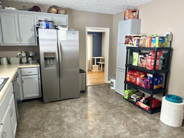 kitchen featuring white cabinetry, stainless steel fridge, and a textured ceiling