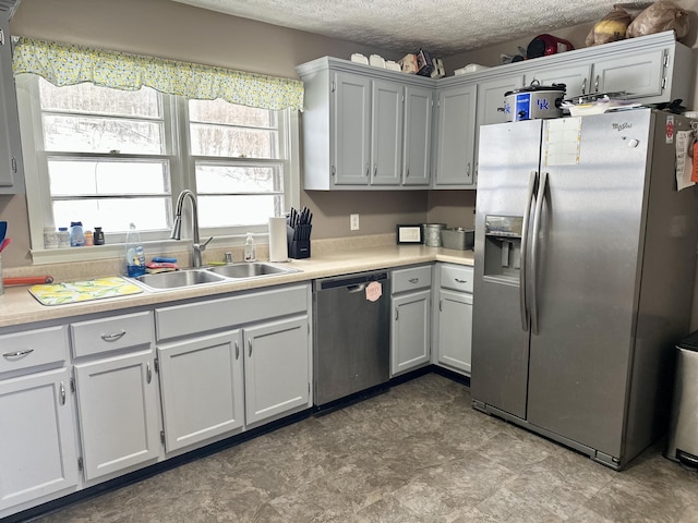 kitchen with stainless steel appliances, sink, a textured ceiling, and white cabinets