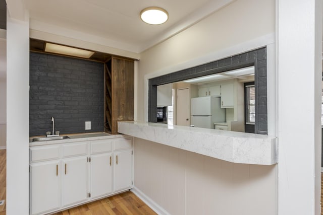 kitchen with sink, white cabinetry, white refrigerator, and light wood-type flooring