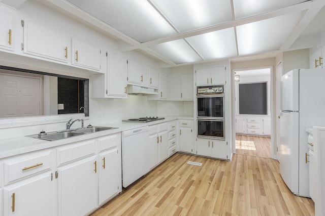 kitchen with sink, white cabinetry, tasteful backsplash, white appliances, and light hardwood / wood-style floors