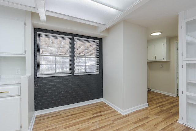 interior space featuring brick wall and light hardwood / wood-style flooring