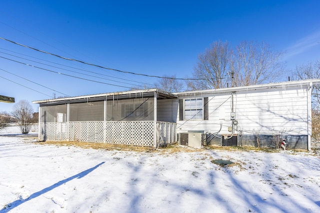 snow covered rear of property featuring cooling unit