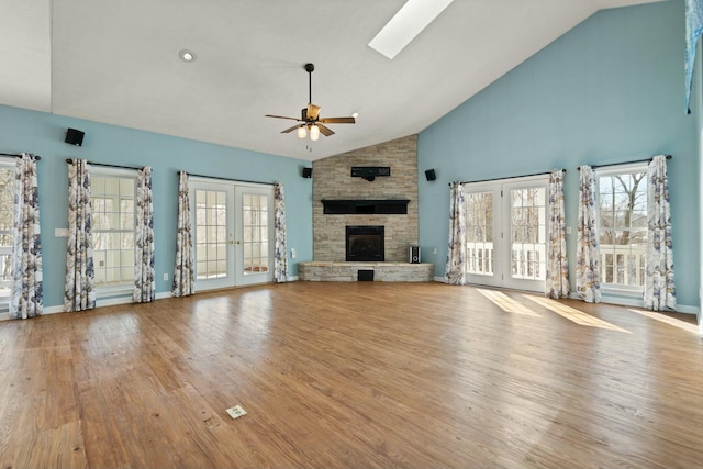 unfurnished living room featuring french doors, a fireplace, light hardwood / wood-style floors, high vaulted ceiling, and ceiling fan