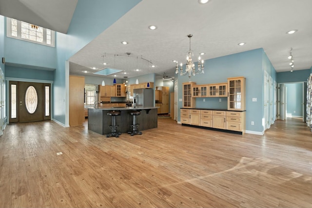 kitchen featuring stainless steel fridge with ice dispenser, decorative light fixtures, a high ceiling, a center island with sink, and a breakfast bar area