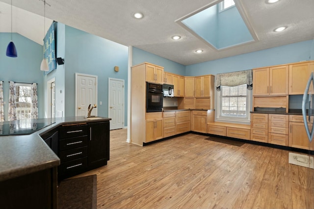 kitchen with light brown cabinetry, hanging light fixtures, sink, light hardwood / wood-style floors, and black appliances