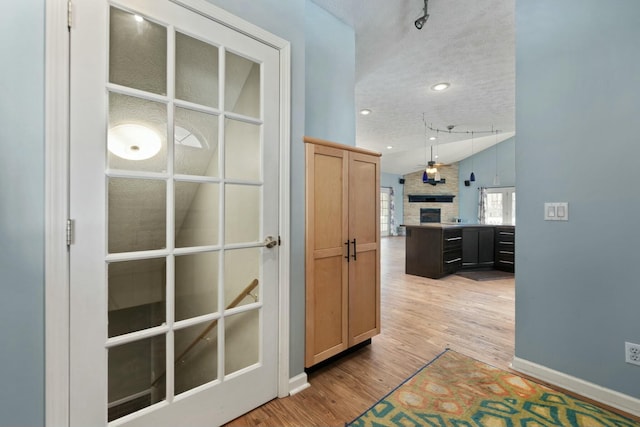 hall with hardwood / wood-style flooring, a textured ceiling, and vaulted ceiling