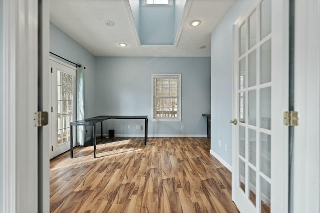 interior space with french doors, a raised ceiling, and wood-type flooring