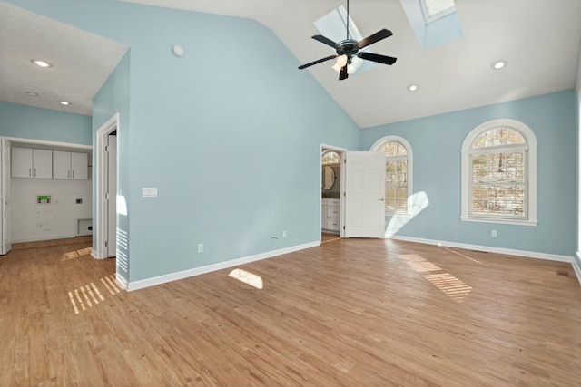 unfurnished living room with a skylight, high vaulted ceiling, ceiling fan, and light hardwood / wood-style floors