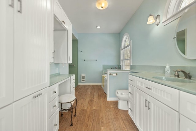 bathroom featuring wood-type flooring, toilet, a bathing tub, and vanity