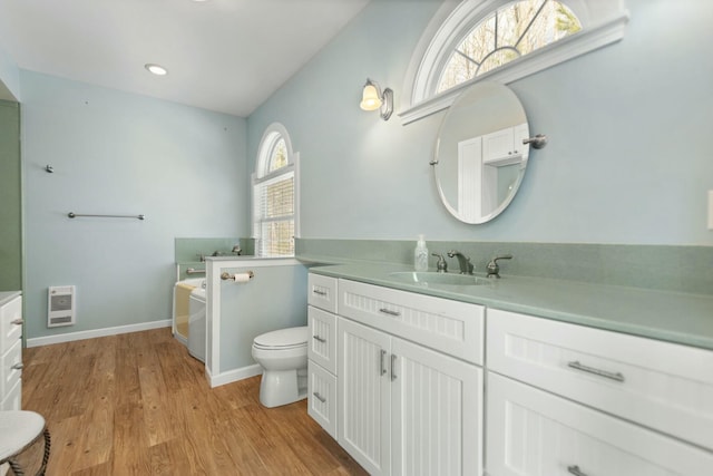 bathroom with hardwood / wood-style flooring, plenty of natural light, toilet, and heating unit