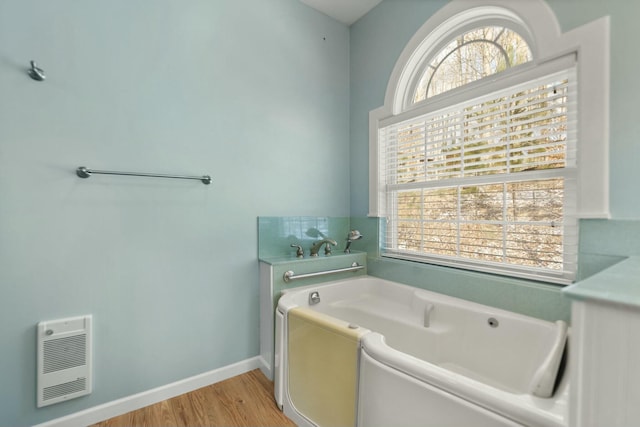 bathroom featuring hardwood / wood-style floors, heating unit, and a bathtub