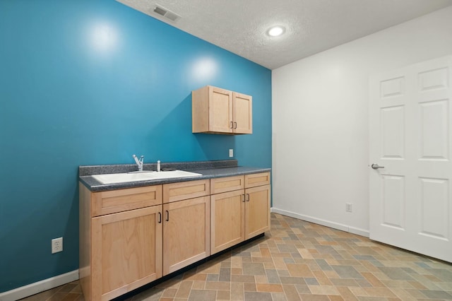 kitchen featuring sink, a textured ceiling, and light brown cabinetry