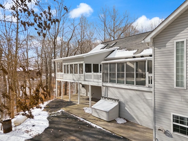 view of snowy exterior featuring a sunroom