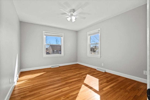 unfurnished room with ceiling fan, wood-type flooring, and a healthy amount of sunlight