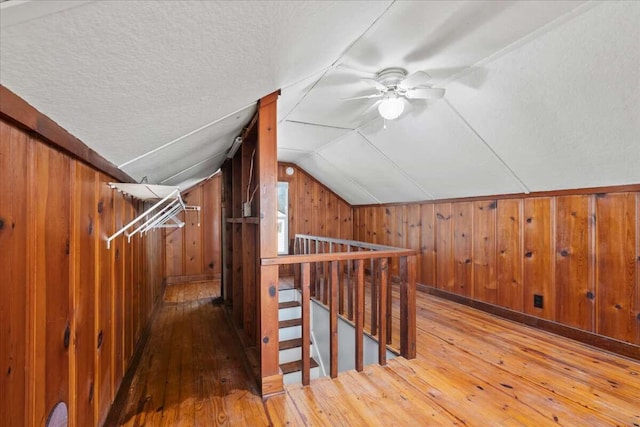 bonus room featuring wood-type flooring, wooden walls, vaulted ceiling, and a textured ceiling