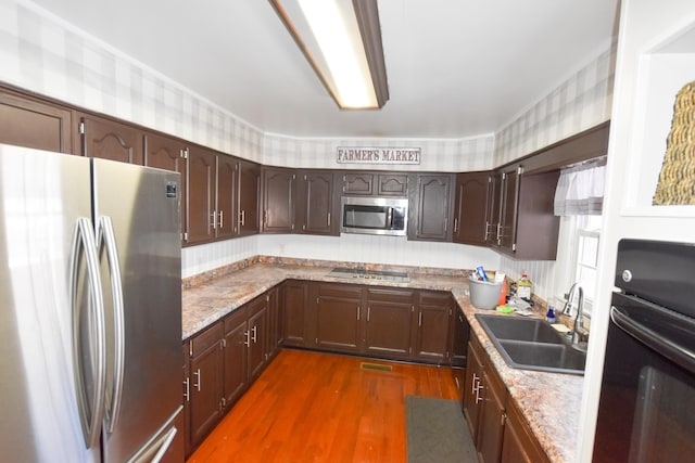 kitchen featuring dark wood-type flooring, sink, light stone counters, and black appliances