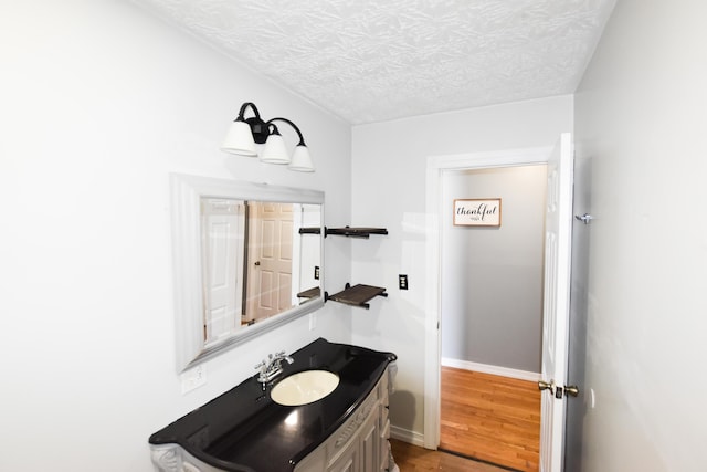 bathroom featuring hardwood / wood-style flooring, vanity, and a textured ceiling