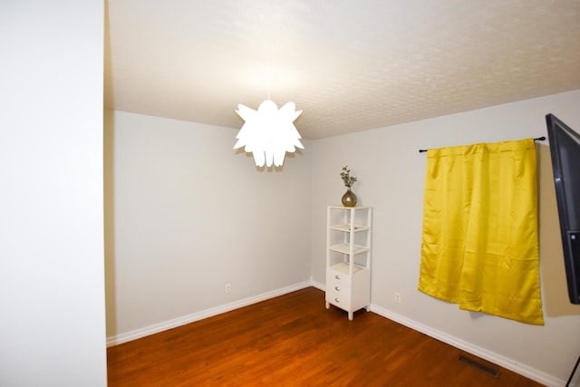 empty room featuring an inviting chandelier and dark wood-type flooring