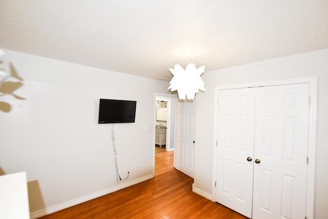 unfurnished bedroom with wood-type flooring, a closet, and a notable chandelier