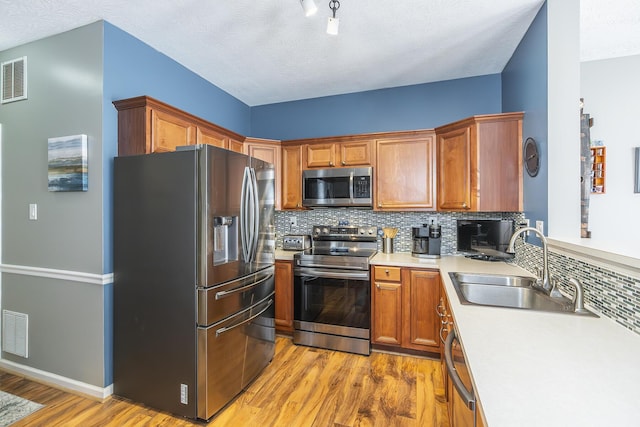 kitchen featuring sink, backsplash, light hardwood / wood-style floors, and stainless steel appliances