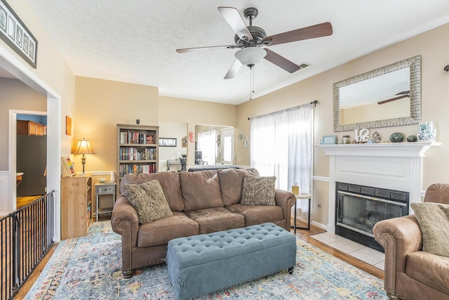 living room featuring light wood-type flooring, a textured ceiling, and ceiling fan