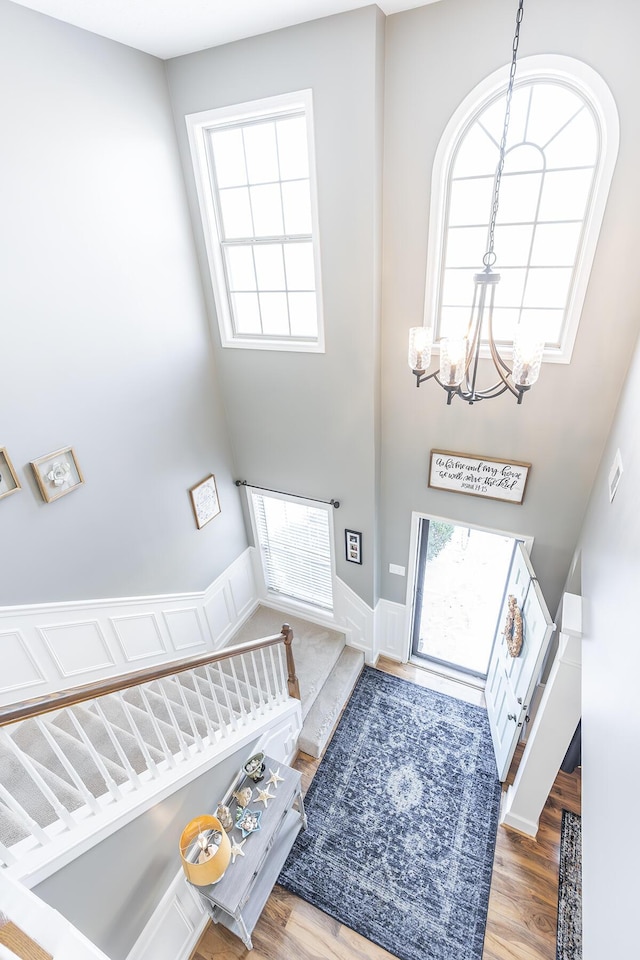 entryway with a high ceiling, hardwood / wood-style flooring, a healthy amount of sunlight, and an inviting chandelier