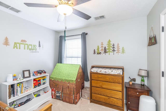 bedroom with ceiling fan, light colored carpet, and a textured ceiling