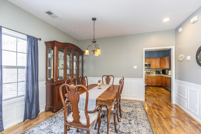 dining area featuring a notable chandelier, light wood-type flooring, and a textured ceiling