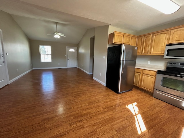 kitchen featuring ceiling fan, stainless steel appliances, vaulted ceiling, and light wood-type flooring