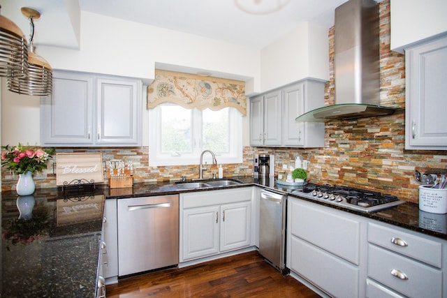 kitchen with decorative backsplash, appliances with stainless steel finishes, dark wood-type flooring, a sink, and wall chimney range hood