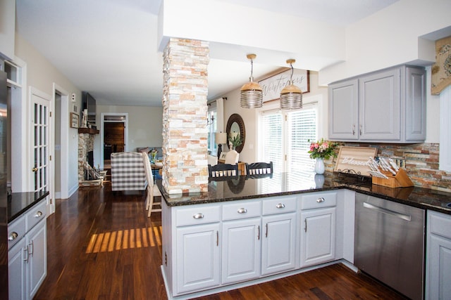 kitchen featuring a peninsula, dark stone countertops, dark wood-style flooring, and dishwasher