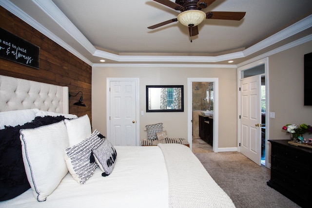 bedroom featuring crown molding, ceiling fan, a raised ceiling, wooden walls, and connected bathroom