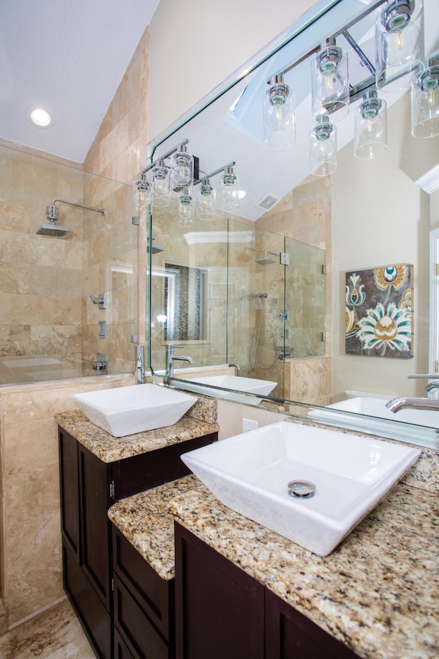 full bath with a stall shower, two vanities, and a sink