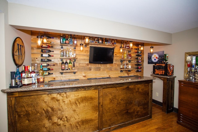 bar with wooden walls, wood finished floors, and wet bar