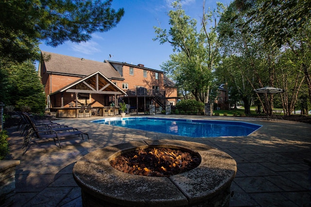 outdoor pool featuring stairs, a patio, and outdoor dry bar