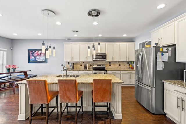 kitchen featuring a kitchen island with sink, decorative light fixtures, and appliances with stainless steel finishes