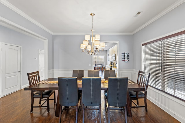 dining room with dark wood-type flooring, ornamental molding, and a chandelier