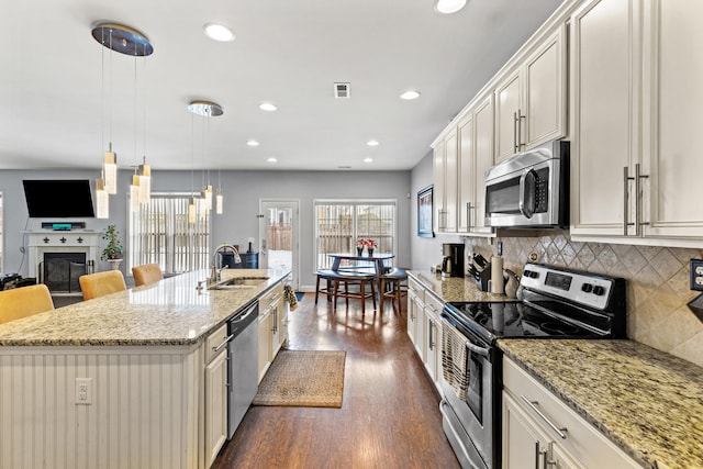 kitchen with sink, a breakfast bar area, hanging light fixtures, a kitchen island with sink, and stainless steel appliances