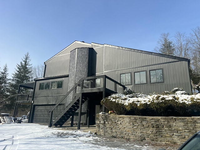 snow covered back of property featuring a garage