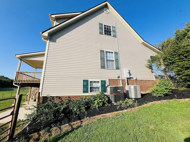 view of property exterior featuring central AC, a yard, and stairs