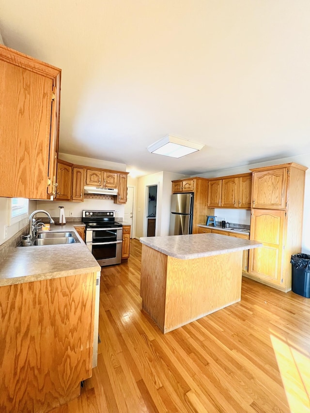 kitchen featuring light wood-style flooring, appliances with stainless steel finishes, a sink, a kitchen island, and under cabinet range hood